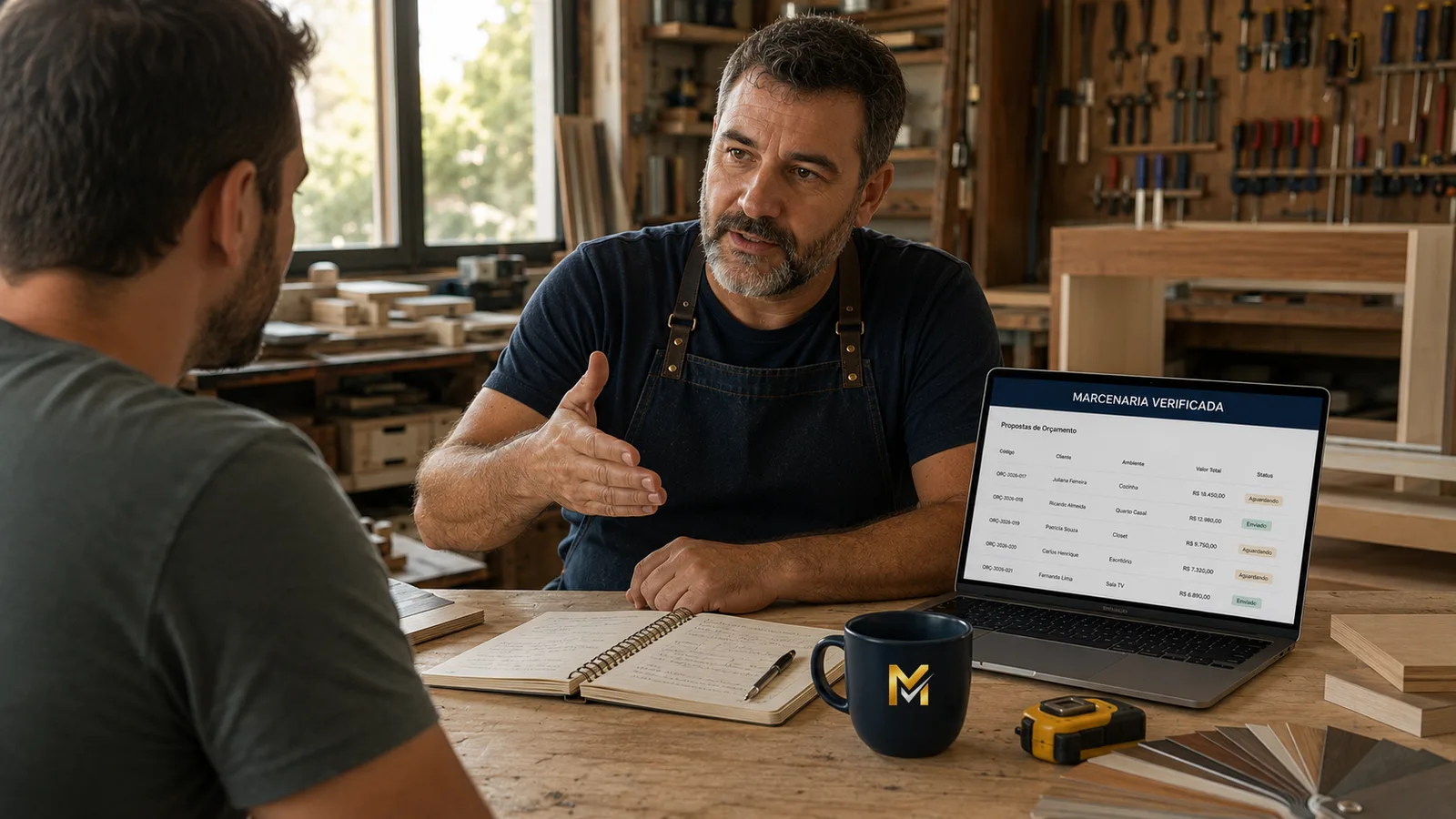 Marceneiro conversando com um cliente na bancada da oficina, com a lista de propostas de orçamento da plataforma aberta no notebook ao lado.